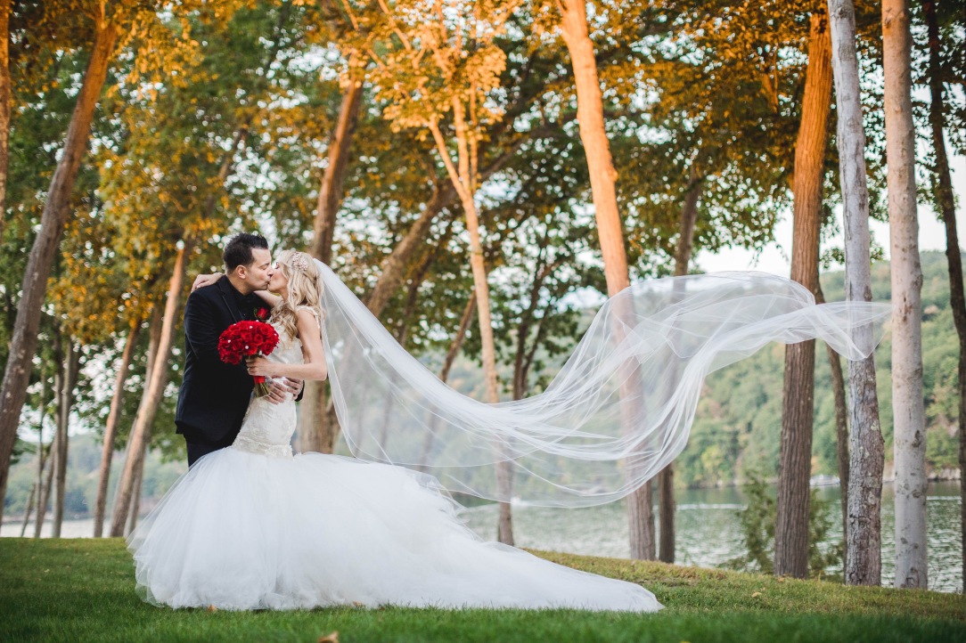 Bride Jenny wears the Lauren Elaine Wisteria gown with cathedral length veil and red bouquet